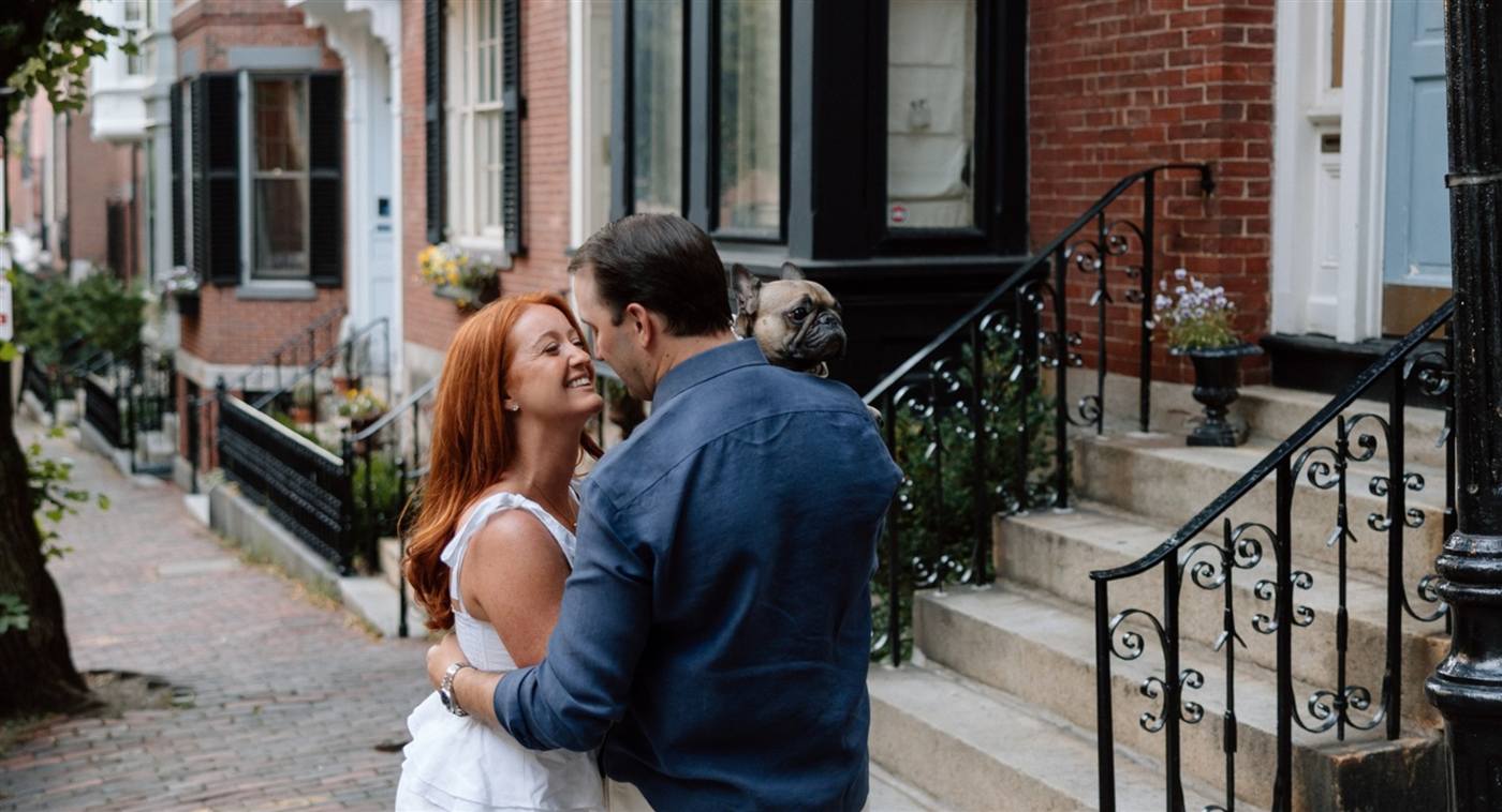 Allison and Daniel on a Beacon Hill sidewalk, holding Shelby, their French bulldog.
